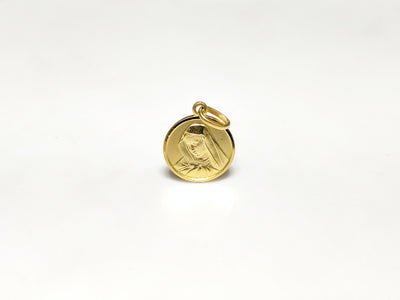 In the center: a portrait of Mary looking downher son Jesus in a 14 karat yellow gold medallion style pendant standing up facing viewer made by Lucky Diamond in New York City