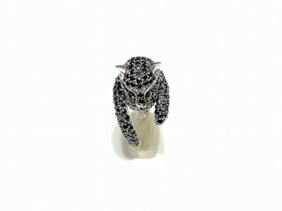 In the center: a sterling silver panther shaped band iced out with black cubic zirconia  in a micro pave setting with its head facing front made by Lucky Diamond in New York City